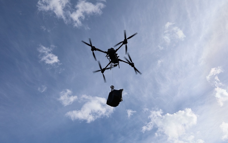 Drone med last mot blå himmel